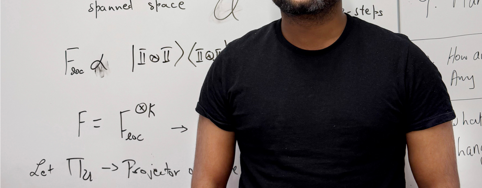 Varun Srivastava stands in front of a whiteboard with equations written on it